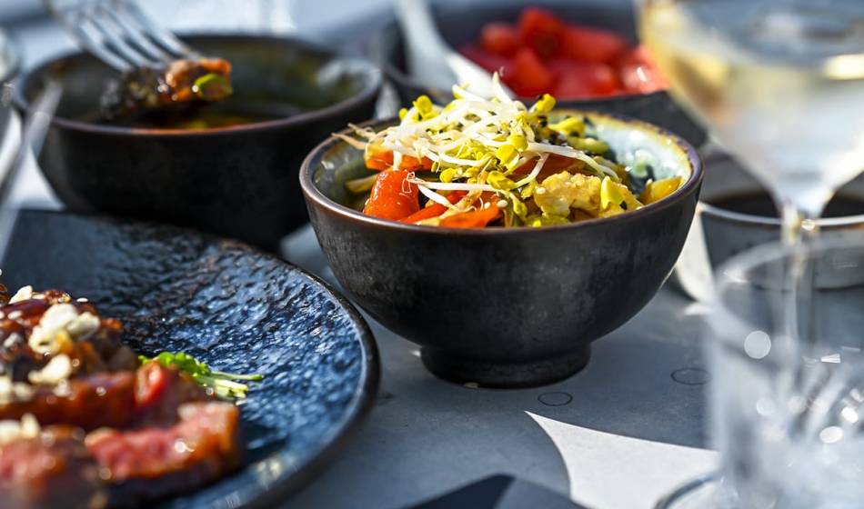 Colorful bowl with fresh ingredients such as sprouts, vegetables and sauce, decoratively arranged for a main course in #herrhoshi.