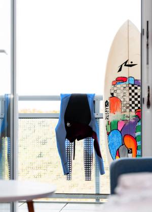 Neoprenanzug und Surfbrett eines Teilnehmers des Surf Cups auf einem Balkon eines Zimmers des Wyn.Strandhotels.
