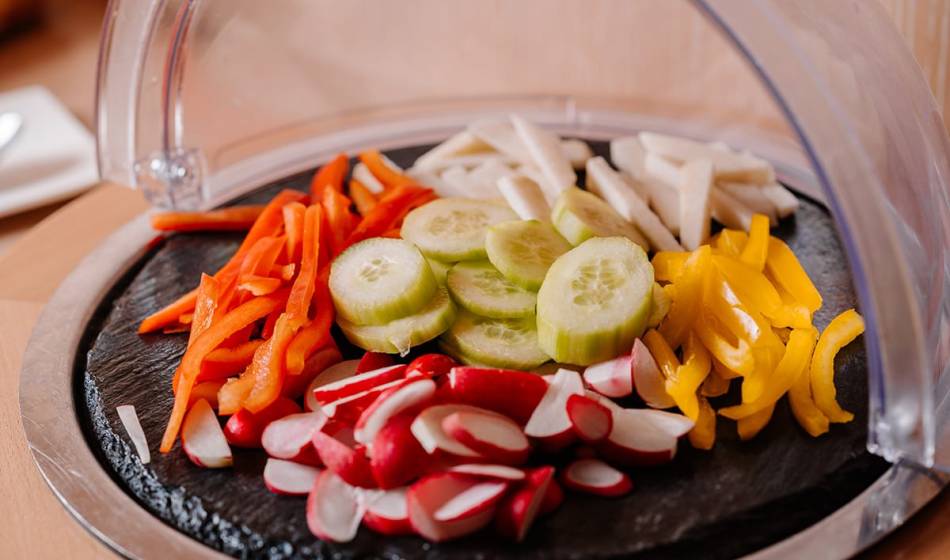 Crisp slices of cucumbers, peppers, radishes and carrots on a decorative slate plate in the Hotel Seezeichen.