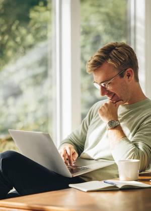 Mann sitzt mit Laptop an einem Tisch und plant den Besuch beliebter Sehenswürdigkeiten für ein Wochenende in Weimar