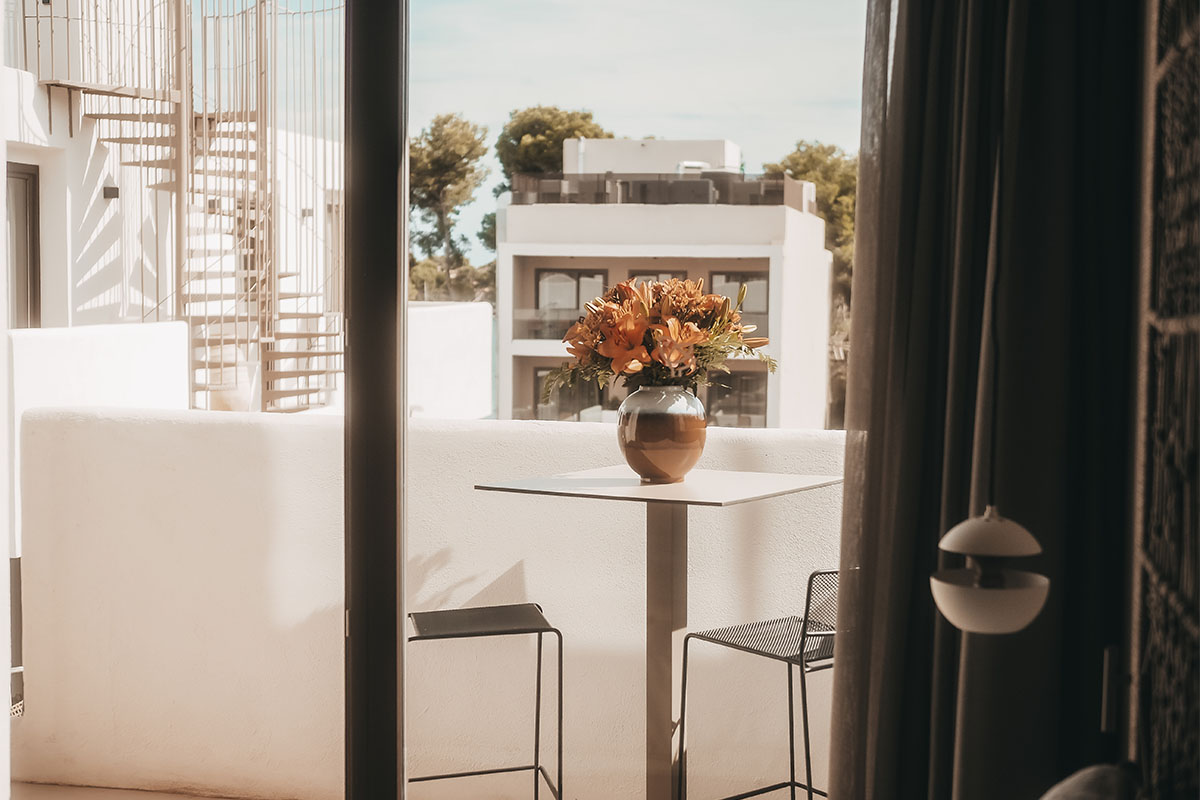Elegant balcony of the Pequeña Suite with table, flower vase and view of the Barefoot Hotel on Mallorca.
