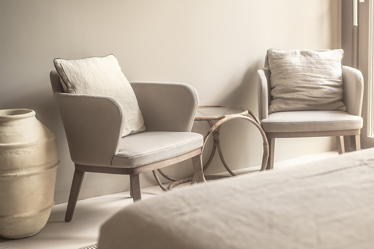 Cozy sitting area with two armchairs, cushions and side table in the Pequeña Suite of the Barefoot Hotel Mallorca.
