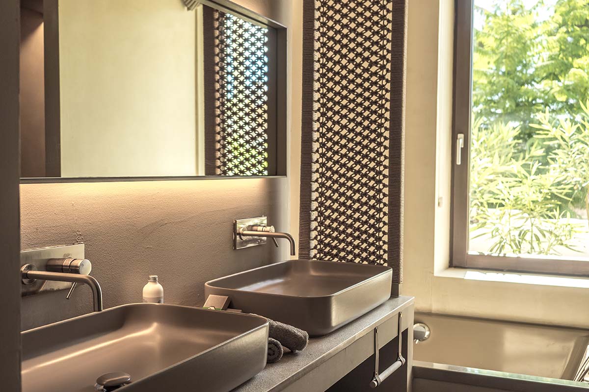 Modern bathroom in the Patio suite at the Barefoot Hotel Mallorca with two washbasins, large mirrors and a view of the greenery