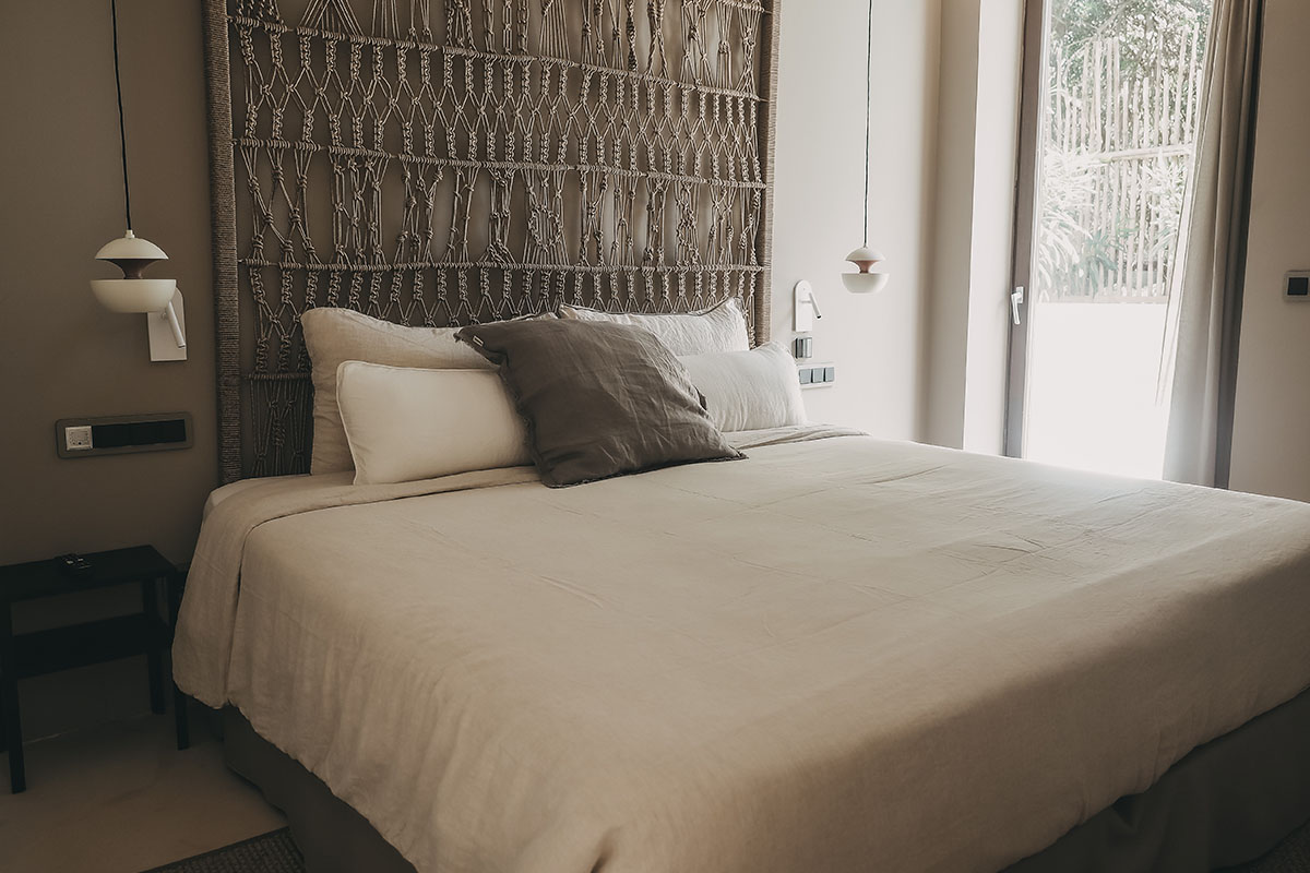 Sleeping area in the Patio suite in the Barefoot Hotel with cozy bed, stylish headboard and view of the greenery.