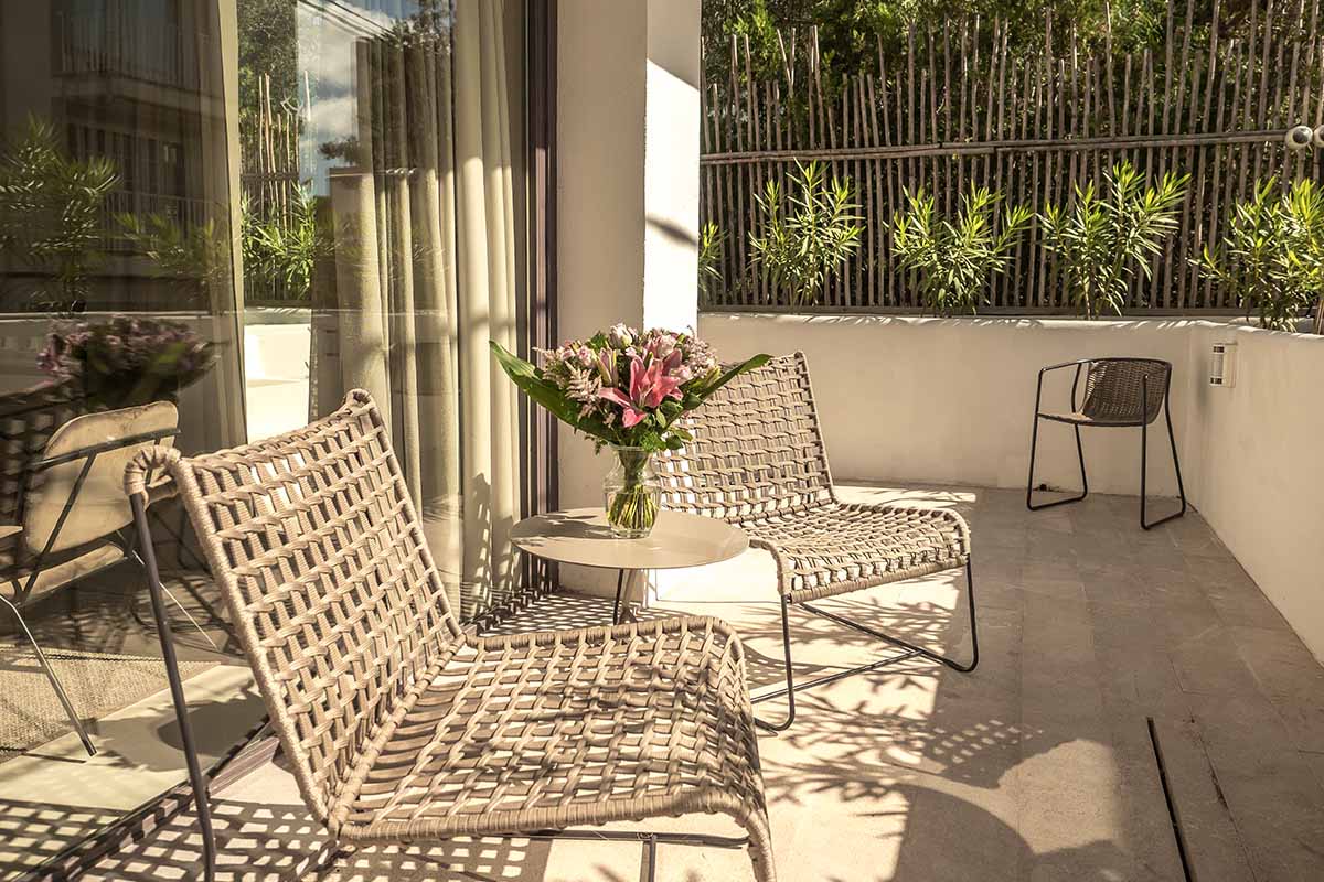 Cozy terrace of the Suite Patio in the Barefoot Hotel Mallorca with elegant chairs, table and a flower arrangement