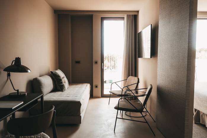 Modernly furnished living area in the Lado Campo Suite in the Barefoot Hotel with a sofa, two armchairs and a view of the terrace.