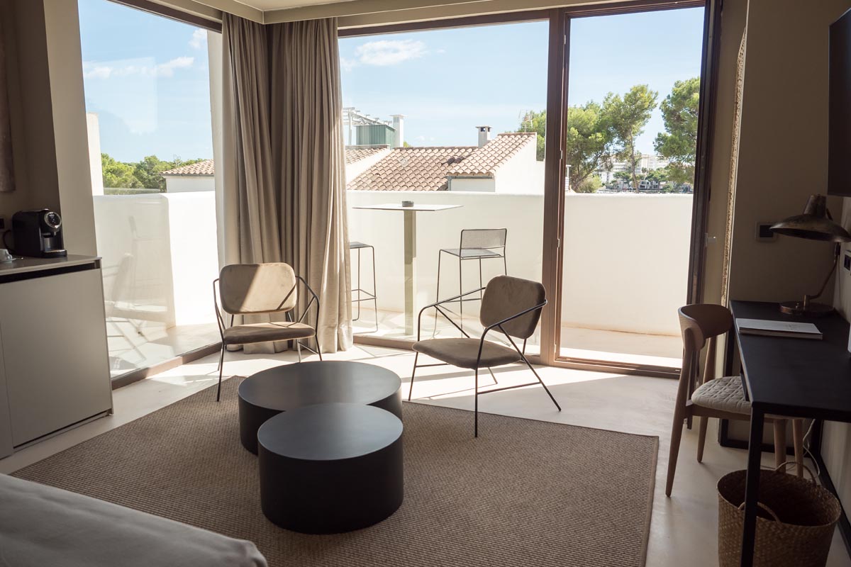 Interior view of a suite in the Barefoot Hotel Mallorca with large windows, seating area and view of the surroundings.