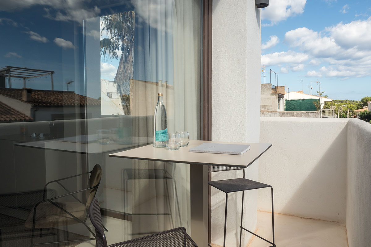 Modern balcony of the suite with table, chairs and view of the surrounding buildings of the Barefoot Hotel on Mallorca.