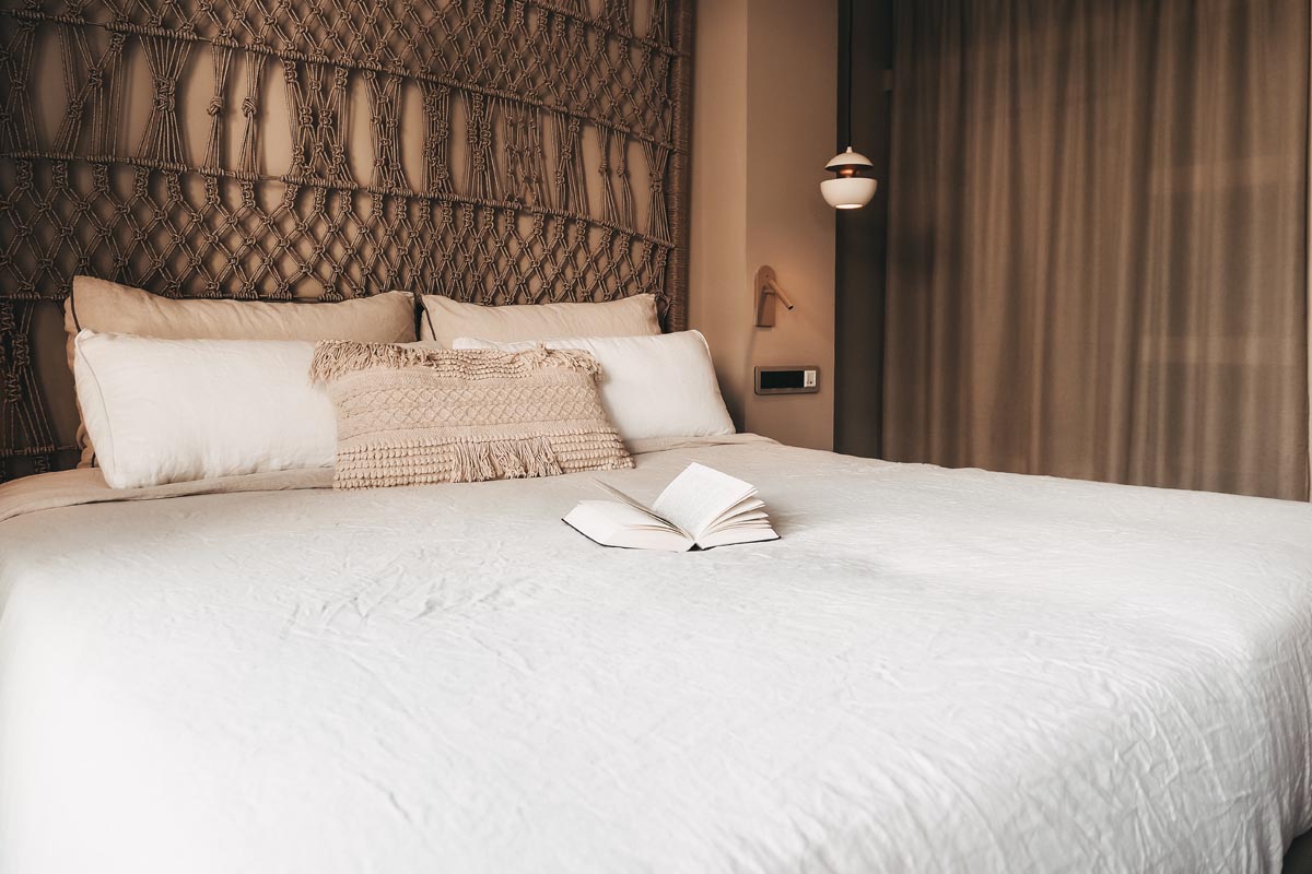 Comfortable double bed in the Puerto double room at the Barefoot Hotel Mallorca with decorative headboard and open book