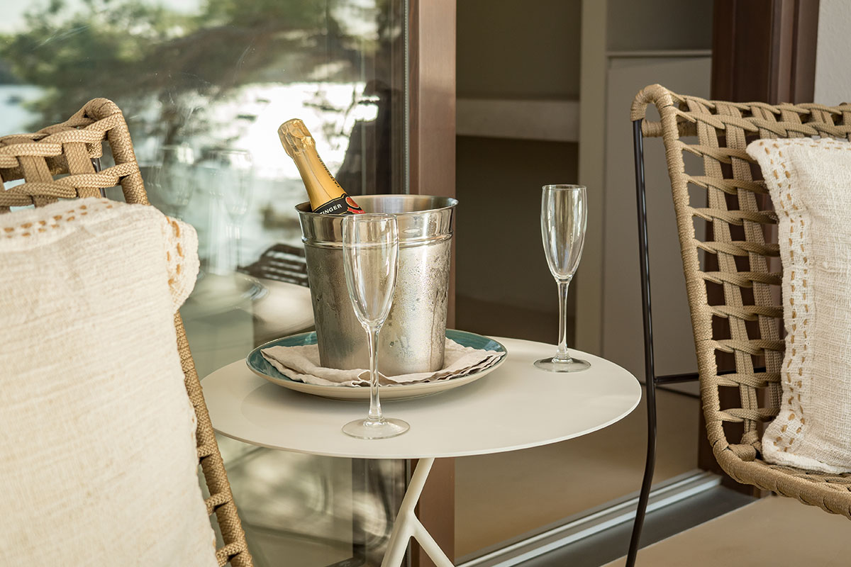 Champagne bottle in a cooler with two glasses on a table on the terrace of the double room Mar at the Barefoot Hotel Mallorca.
