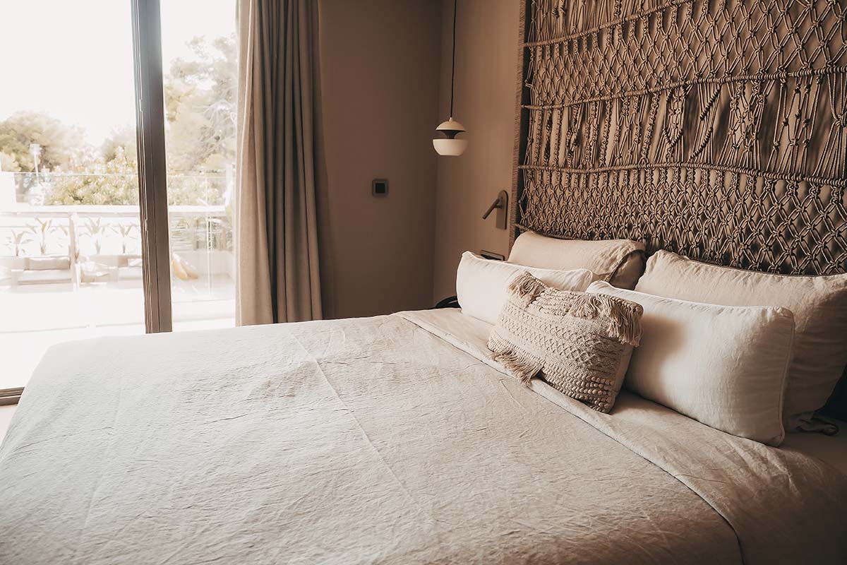 Large double bed in the Deluxe Double Room Oasis at the Barefoot Hotel Mallorca with decorative headboard, soft pillows and balcony view.