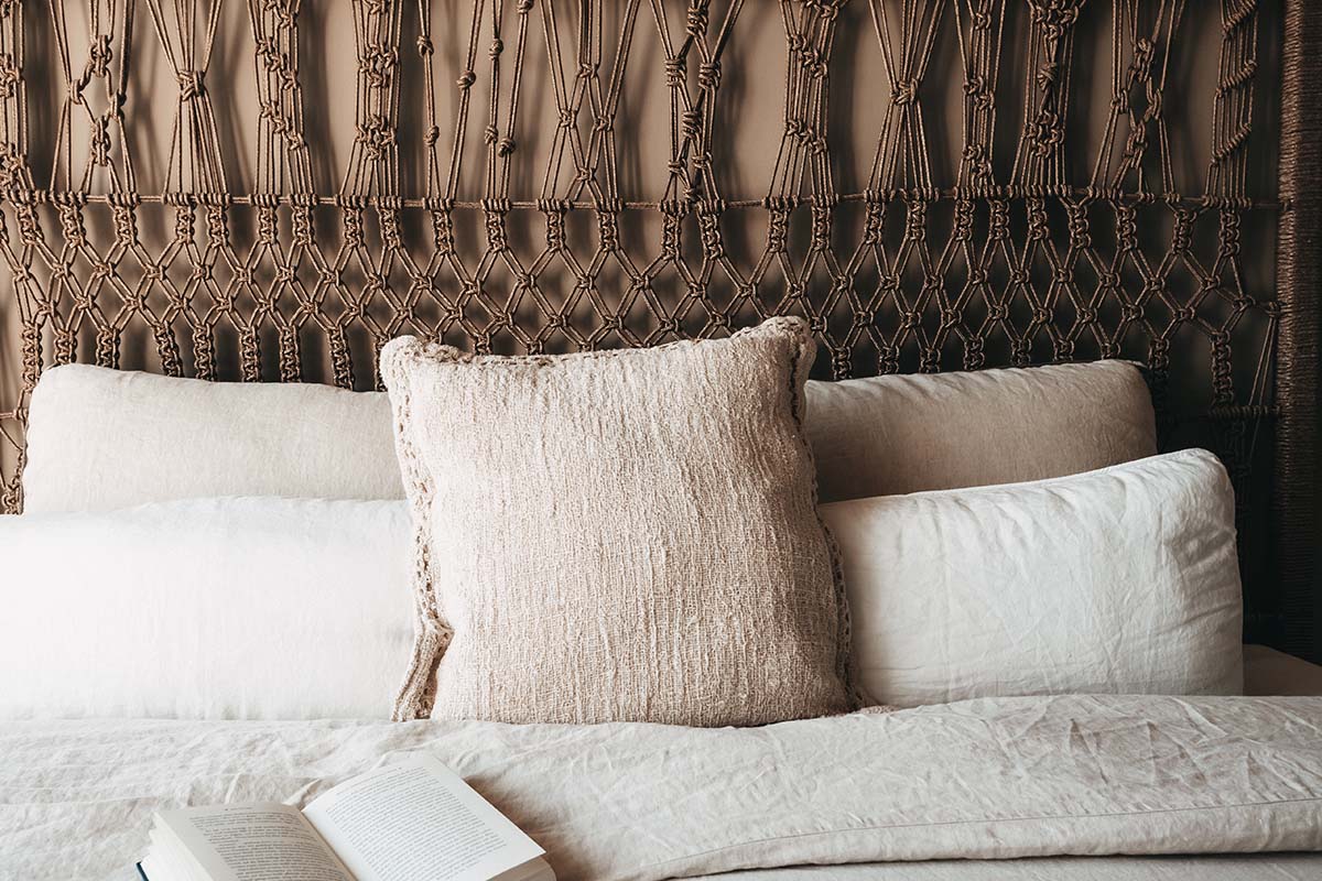 Decorative cushions and an open book on a cozy double bed in the Oasis double room at the Barefoot Hotel on Mallorca.