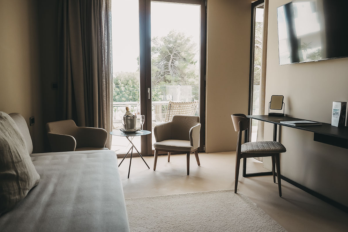 Living area in the Deluxe Double Room Oasis of the Barefoot Hotel on Mallorca with sofa, armchairs, desk and access to the balcony.