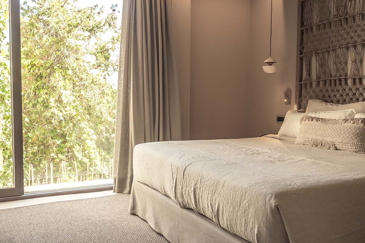 Hotel room Puro with a large, cozy bed and a view of green trees at Barefoot Hotel Mallorca.