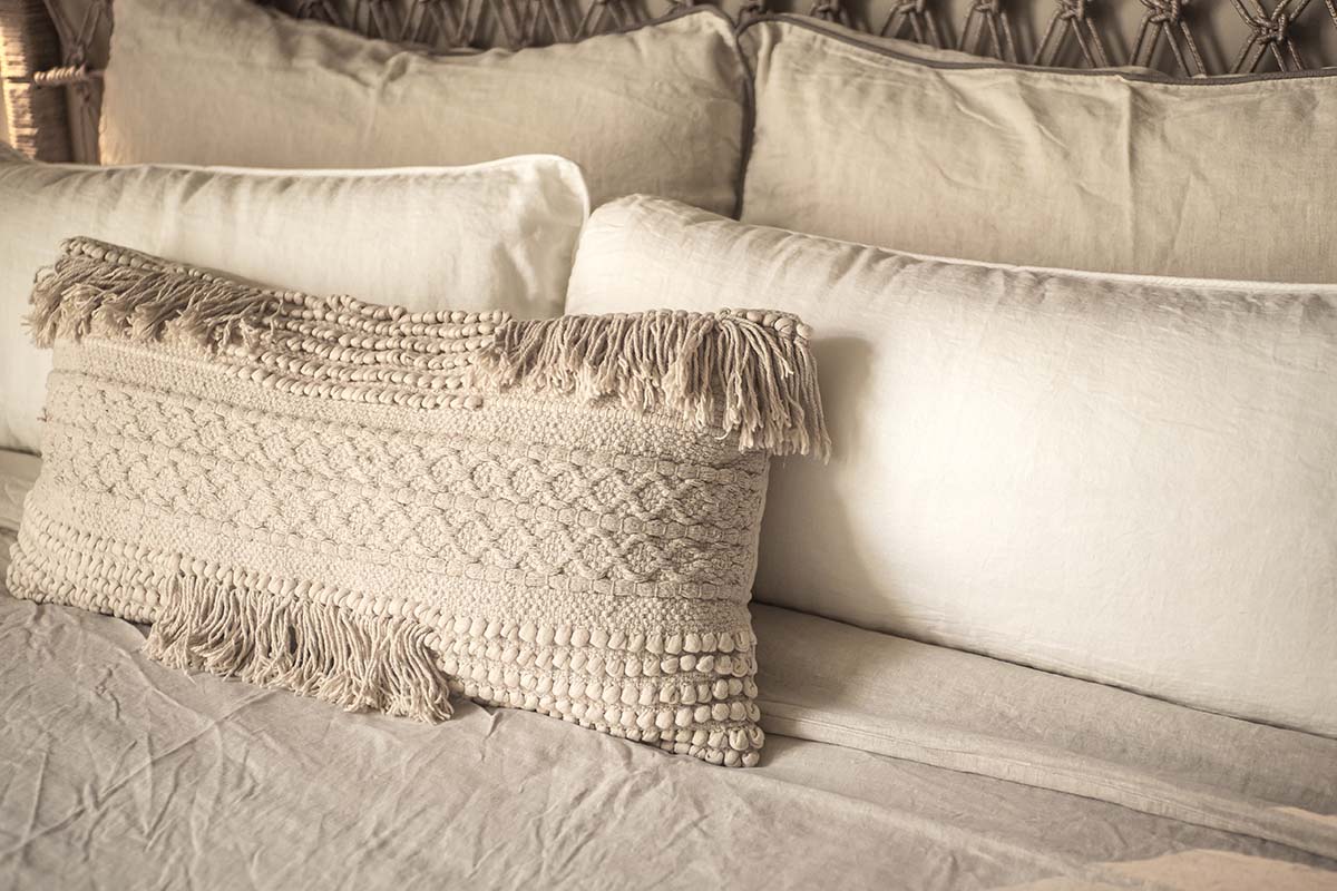Textured cushion made of natural materials on a bed in the Barefoot Hotel Mallorca for a relaxed ambience.