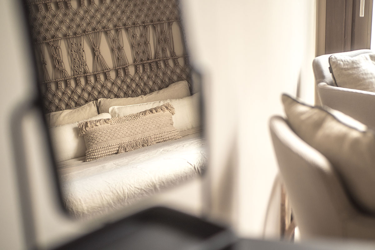 Mirror reflection of the Puro hotel room with macramé bed headboard, beige cushions and natural materials at the Barefoot Hotel Mallorca.