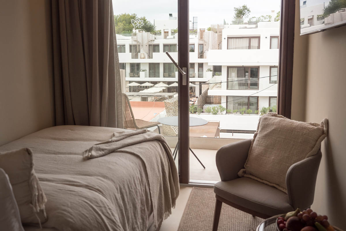Dormitory room at Barefoot Hotel Mallorca with single bed, armchair and balcony overlooking the hotel grounds.