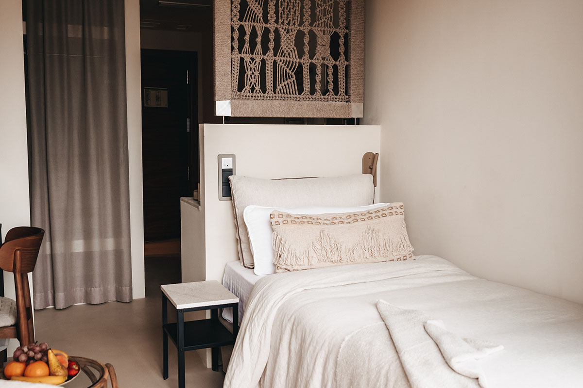 Modern Dormitorio room in the Barefoot Hotel Mallorca with cozy single bed, white textiles and boho tapestry.