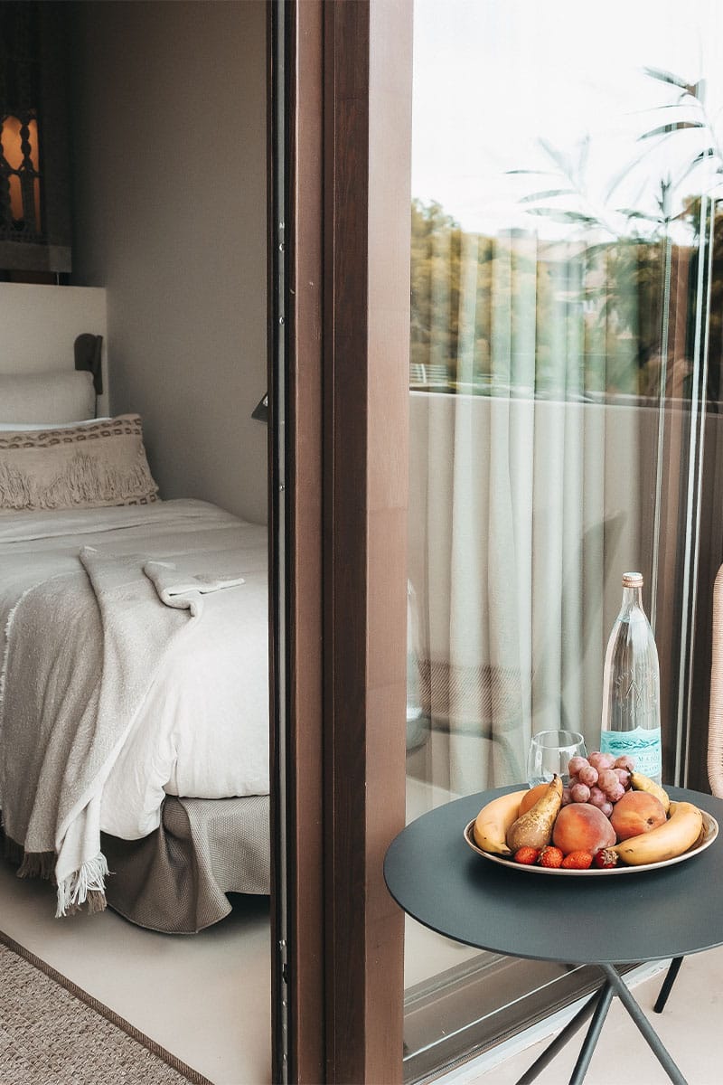 Dormitorio room at Barefoot Hotel Mallorca with balcony view, table with fruit bowl and water bottle.