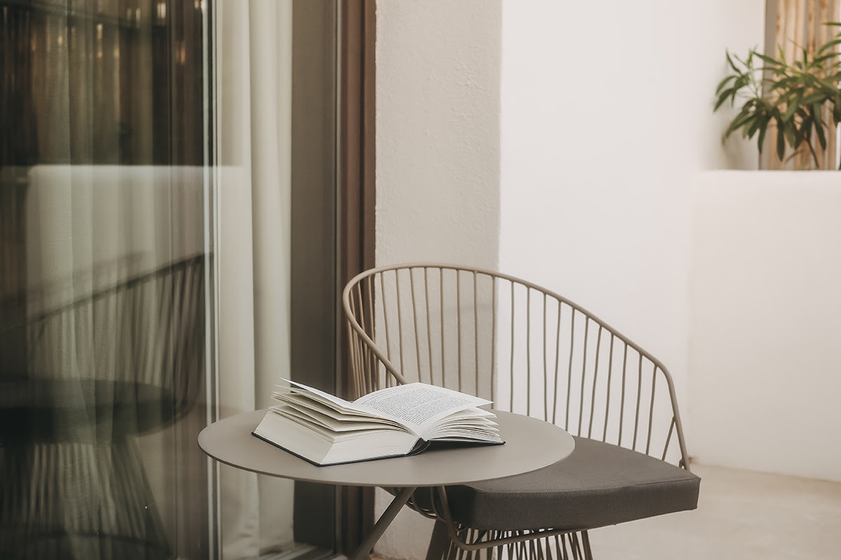 Cosy balcony in the Pino room at the Barefoot Hotel Mallorca with seating, table and open book.
