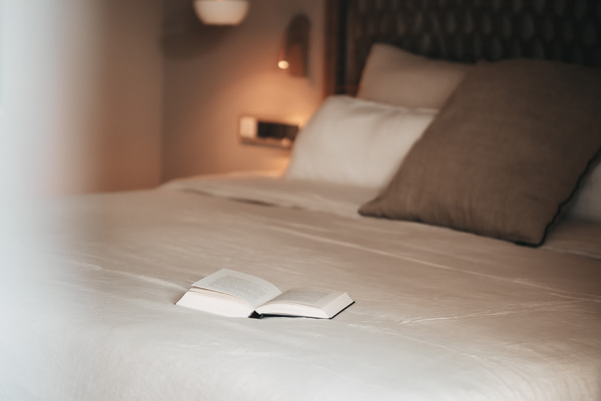 Sleeping area in the Pino room at the Barefoot Hotel Mallorca with an open book on a large bed and cozy pillows.