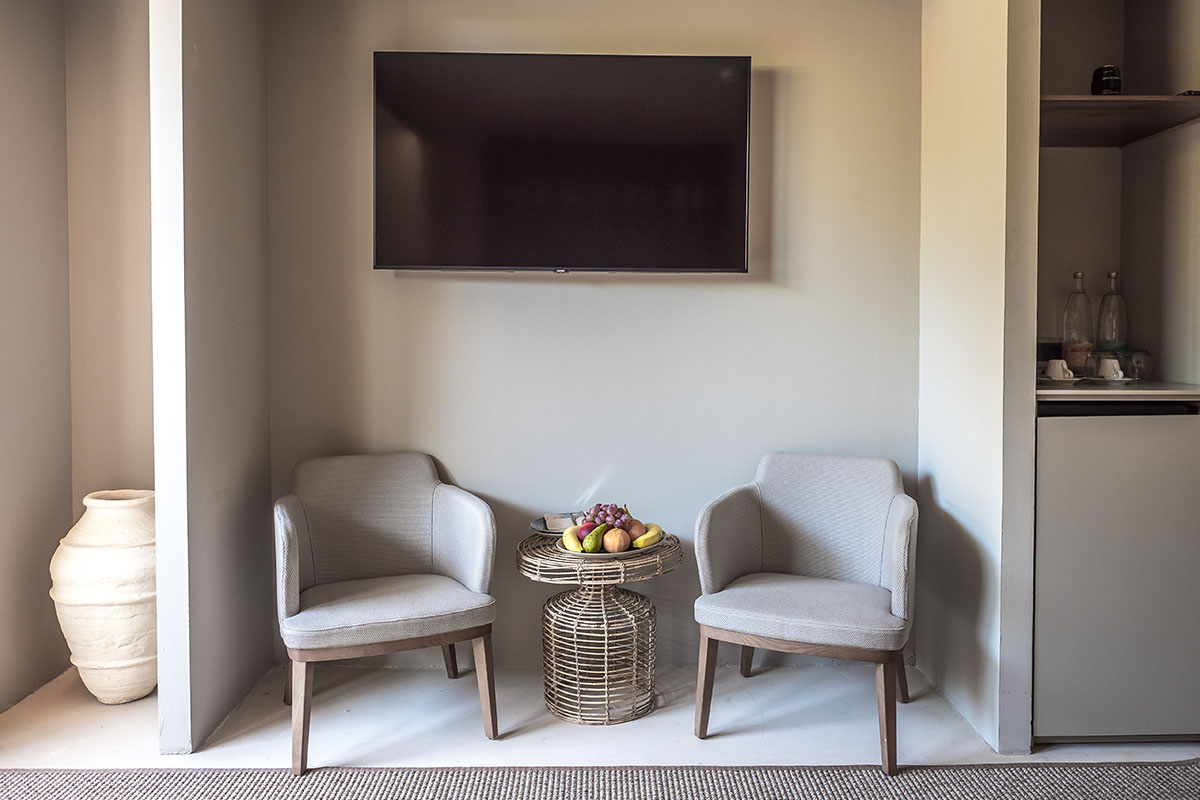 Cozy sitting area in the Pino room of the Barefoot Hotel Mallorca with two armchairs, rattan table and fruit bowl.