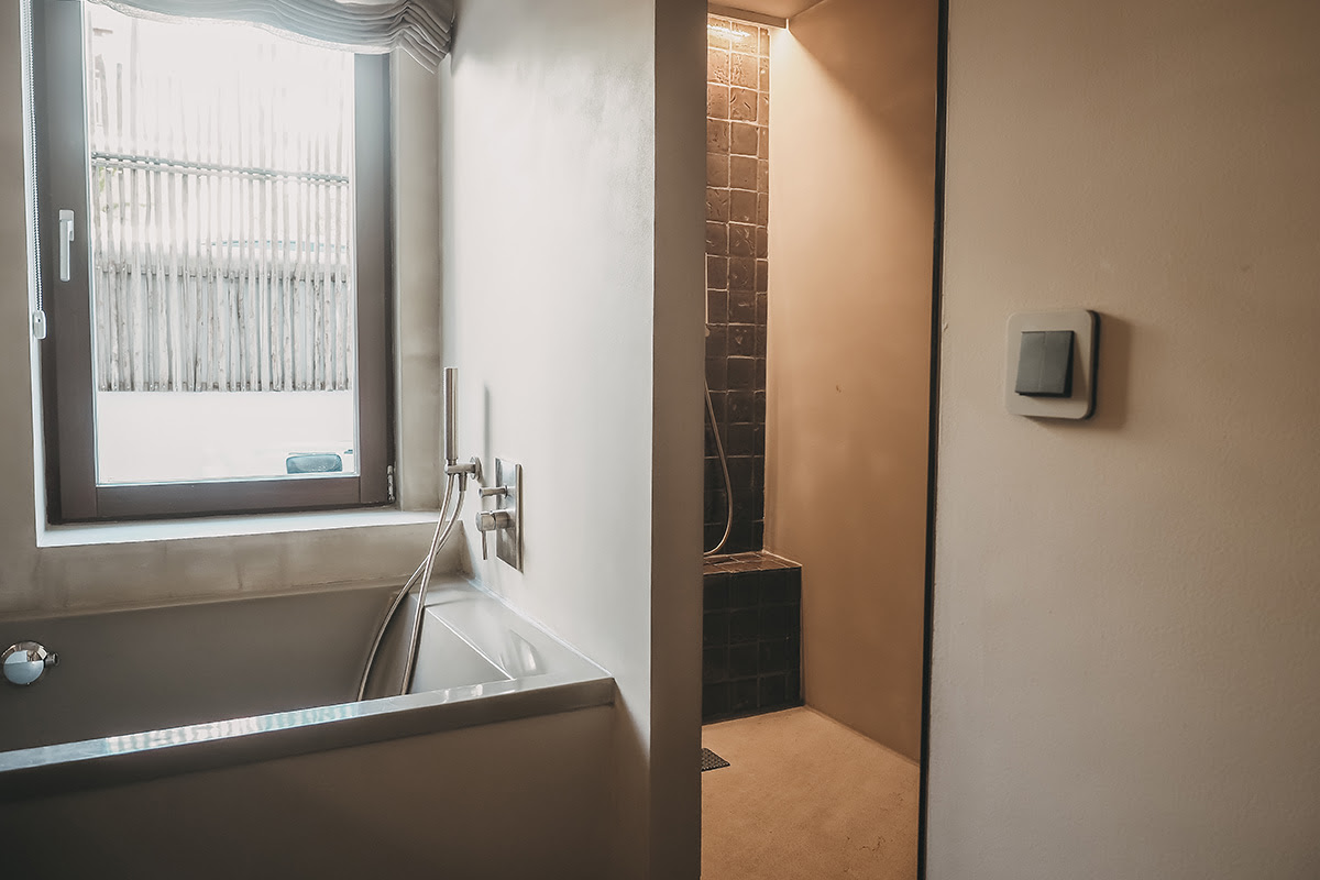 Bright bathroom with bathtub and walk-in shower in the Pueblo room of the Barefoot Hotel Mallorca for relaxing wellness moments.