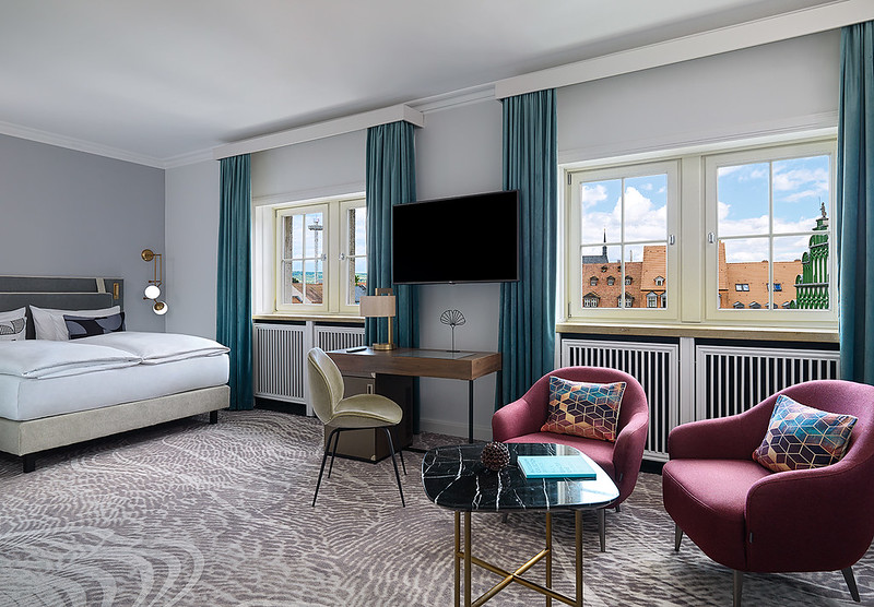 Elegant hotel room at the Hotel Elephant Weimar with a view of the historic old town and a cozy, modern interior.