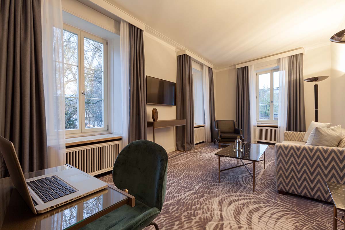 Elegant living room with modern furnishings and a view of the garden in the Executive Suite at the Hotel Elephant Weimar.