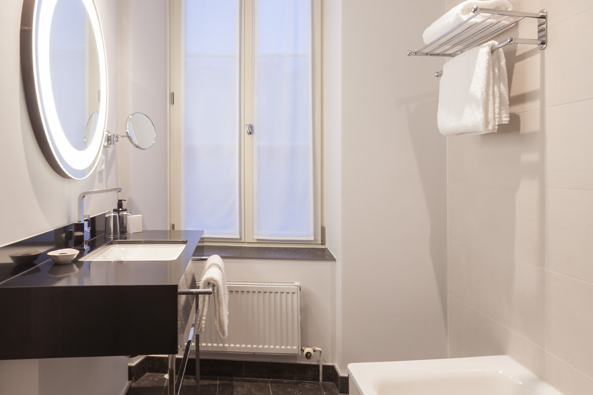 Bright bathroom with large washbasin and illuminated mirror in the Executive Suite at Hotel Elephant.
