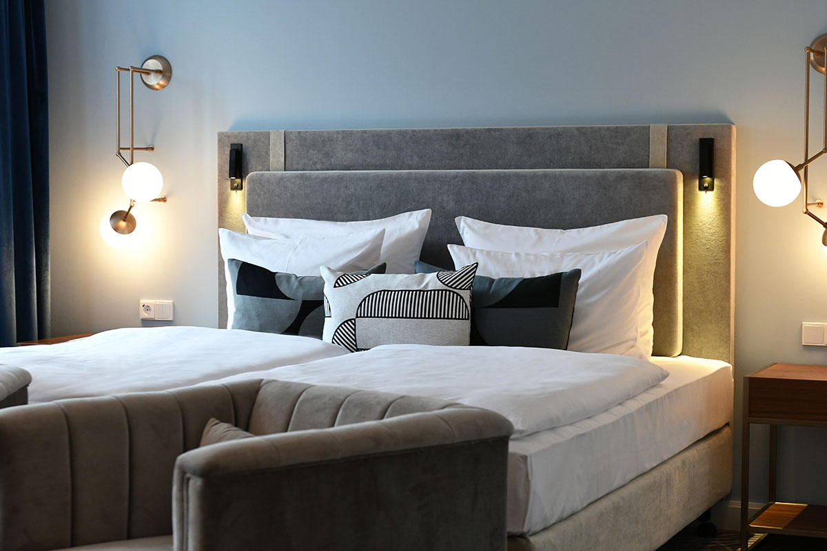 Large, stylishly furnished double bed with soft pillows and warm light in the Executive Suite at the Hotel Elephant Weimar.