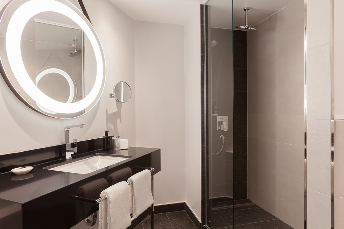 Modern bathroom in the junior suite of the Hotel Elephant Weimar with elegant shower and illuminated mirror.