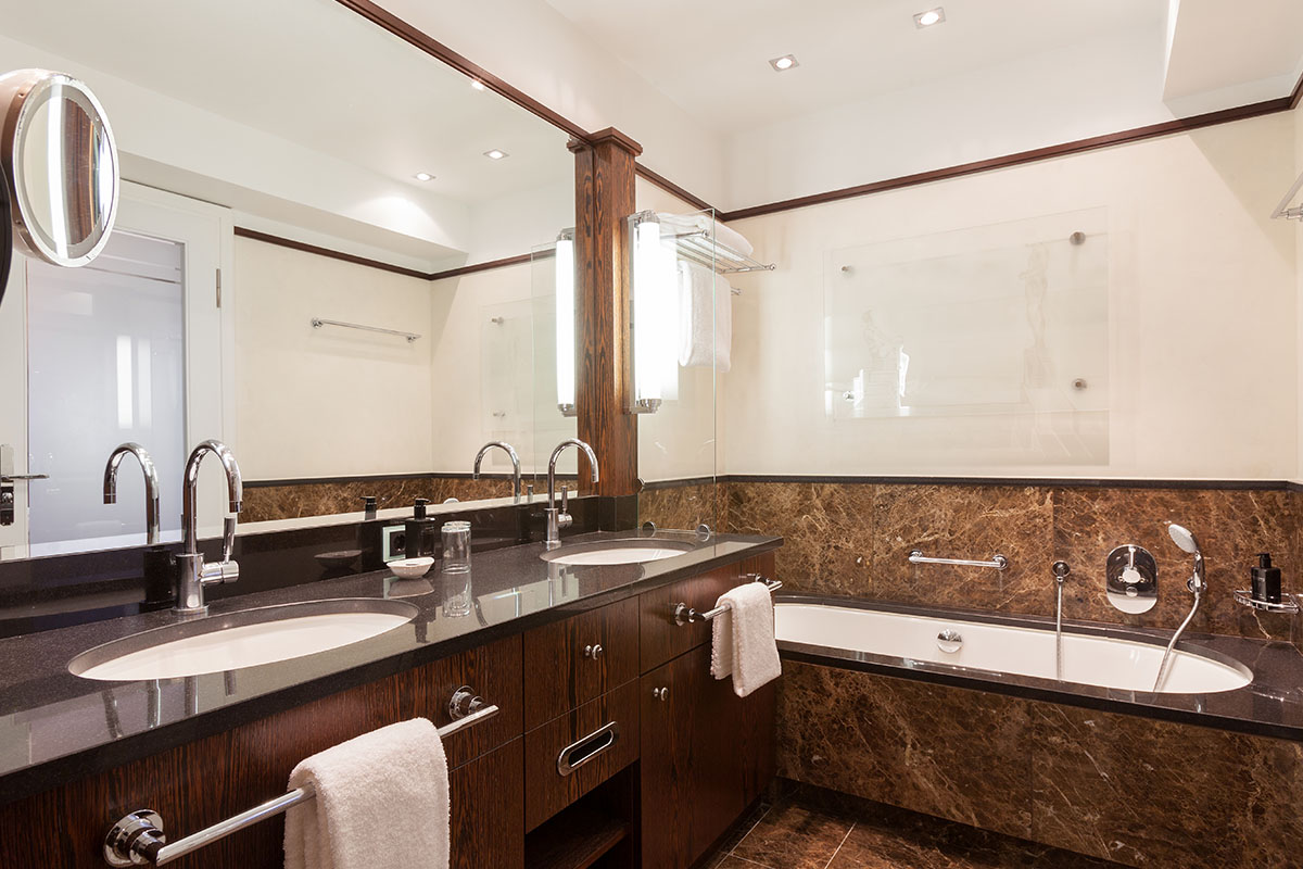 Bathroom of the Thomas Mann Suite at the Hotel Elephant Weimar with double washbasin, luxurious bathtub and stylish wooden details.