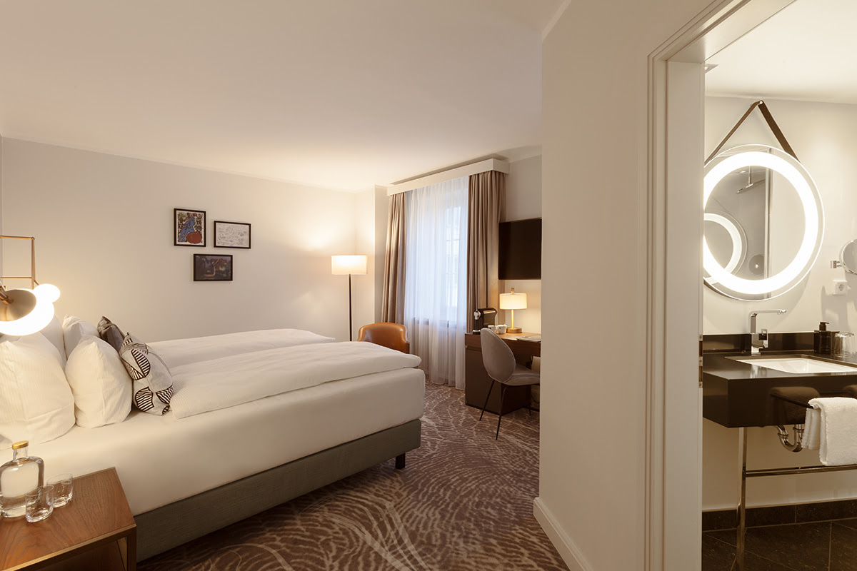 Deluxe-Zimmer im Hotel Elephant Weimar mit modernem Design, einem großen Bett und persönlichem Badezimmer.