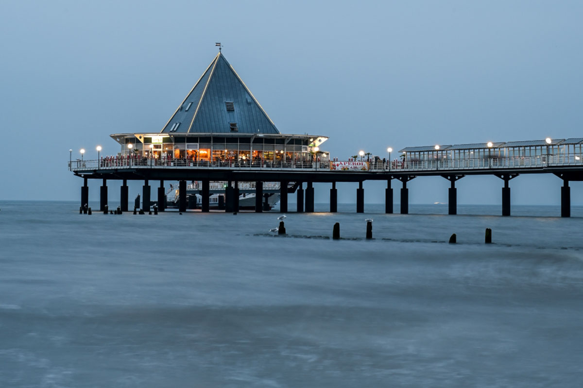 Pier in Heringsdorf with illuminated railings and a peaceful atmosphere at dusk.