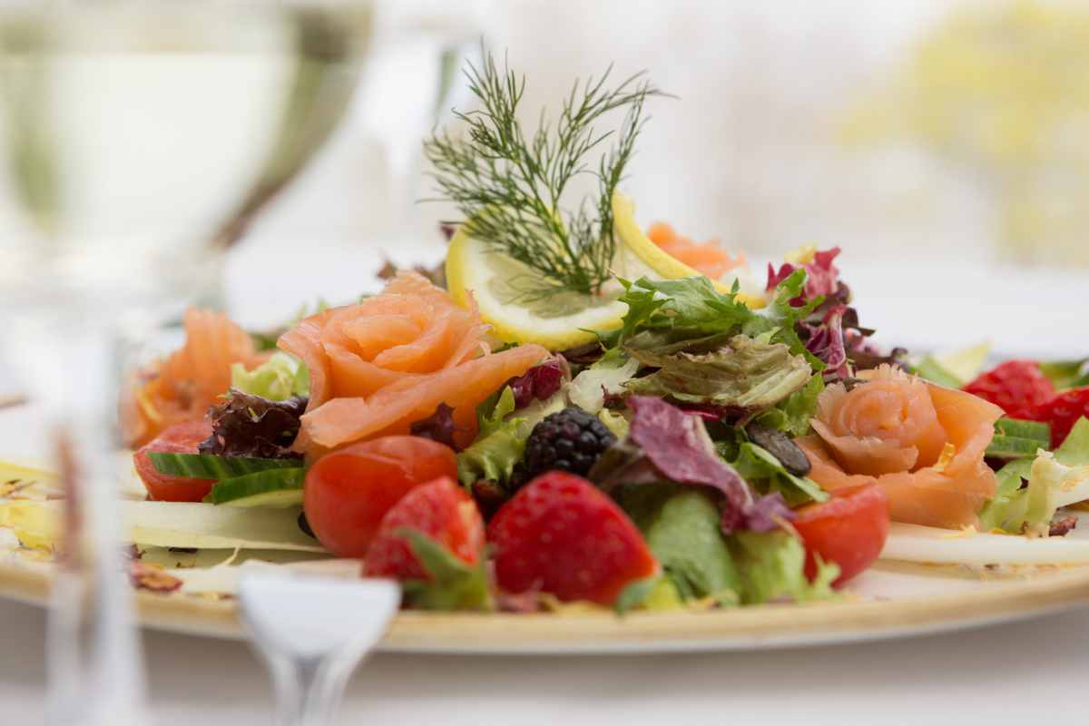 Teller mit frischem Lachs, Beeren und Salat, liebevoll angerichtet im Palmengarten des Hotel Kaiserhof Heringsdorf.