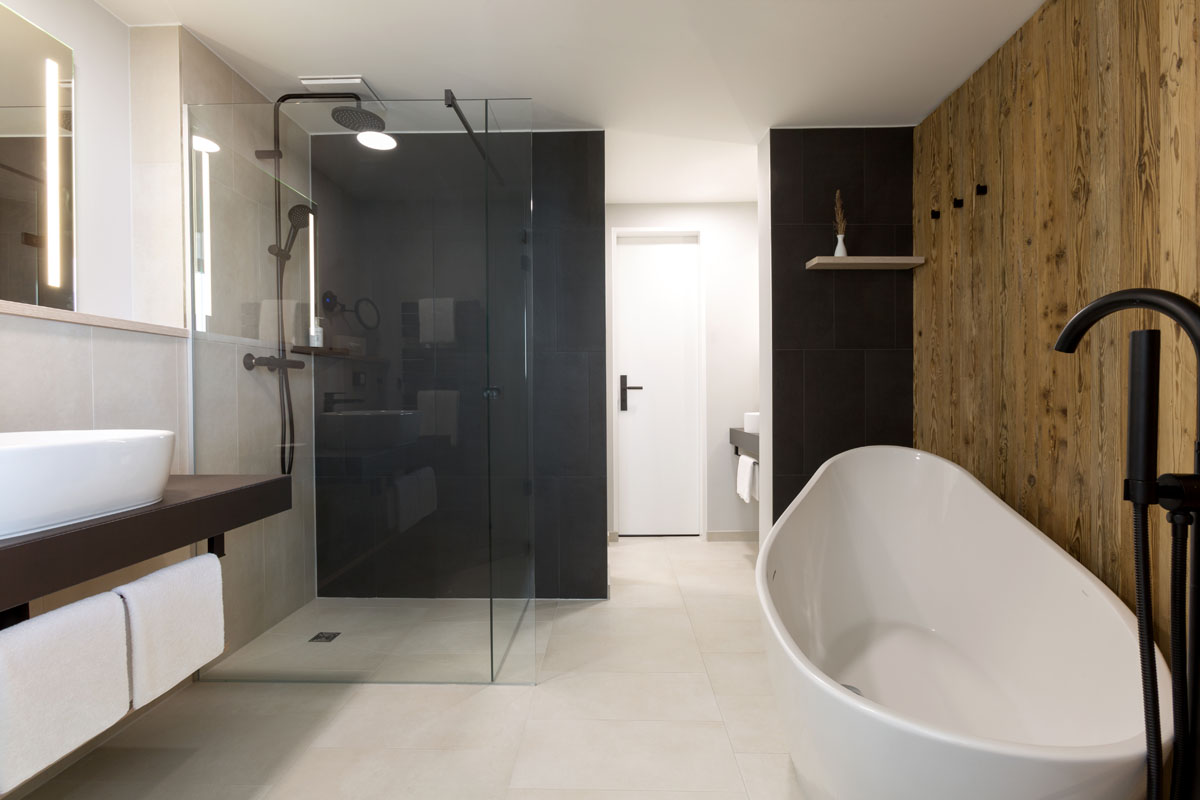Badezimmer der Kaisersuite mit freistehender Badewanne, Regenwalddusche und stilvoller Holzverkleidung im Hotel Kaiserhof.