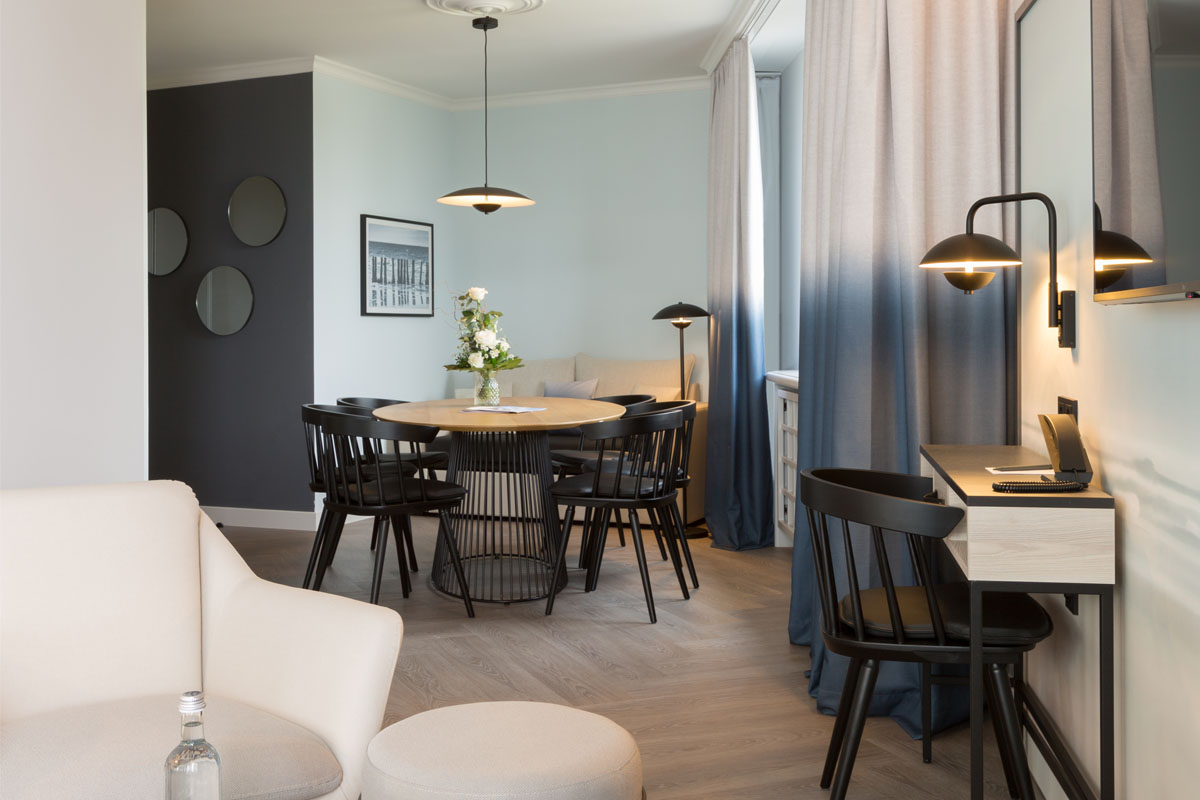 Wohnbereich der Kaisersuite mit Esstisch, Stühlen, Schreibtisch und modernem Design, ideal für Arbeit und Erholung im Hotel Kaiserhof.