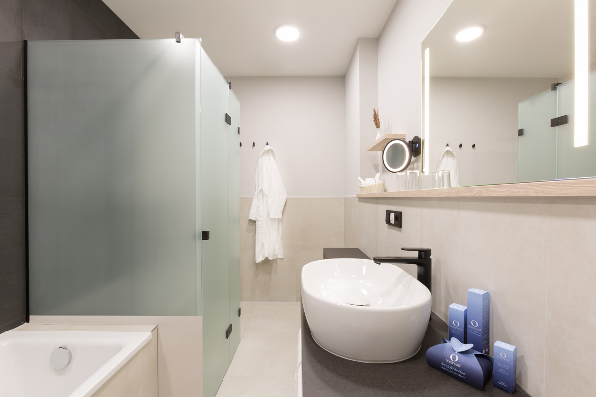 Modernes Badezimmer der Themensuite mit Waschtisch, Spiegel und Dusche im Hotel Kaiserhof Heringsdorf auf Usedom.