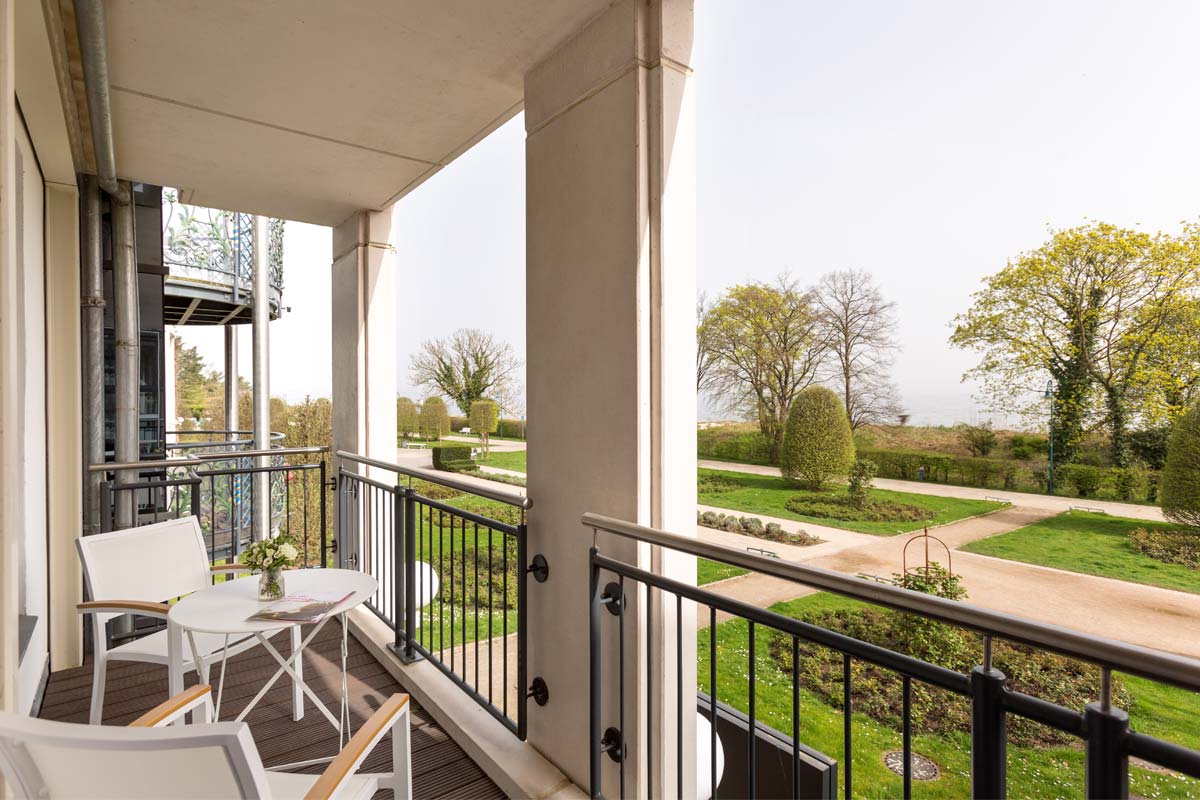 Balkon einer Themensuite im Hotel Kaiserhof Heringsdorf auf Usedom mit Tisch, Stühlen und Blick auf den Garten.