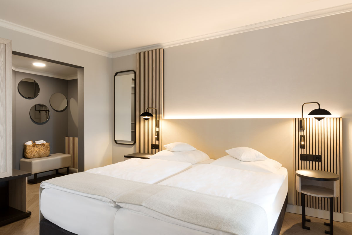 Modernes Doppelbett in der Themensuite des Hotel Kaiserhofs Heringsdorf mit eleganter Beleuchtung und minimalistischem Design.