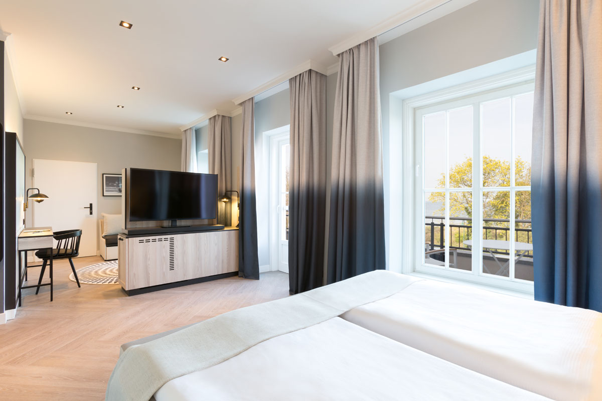 Blick in den Schlafbereich einer Themensuite mit Doppelbett und Balkon im Hotel Kaiserhof Heringsdorf auf Usedom.