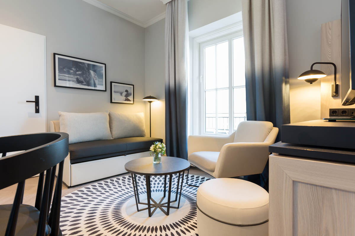 Moderner Sitzbereich mit Sofa, Sessel und rundem Tisch in einer Themensuite im Hotel Kaiserhof Heringsdorf auf Usedom.
