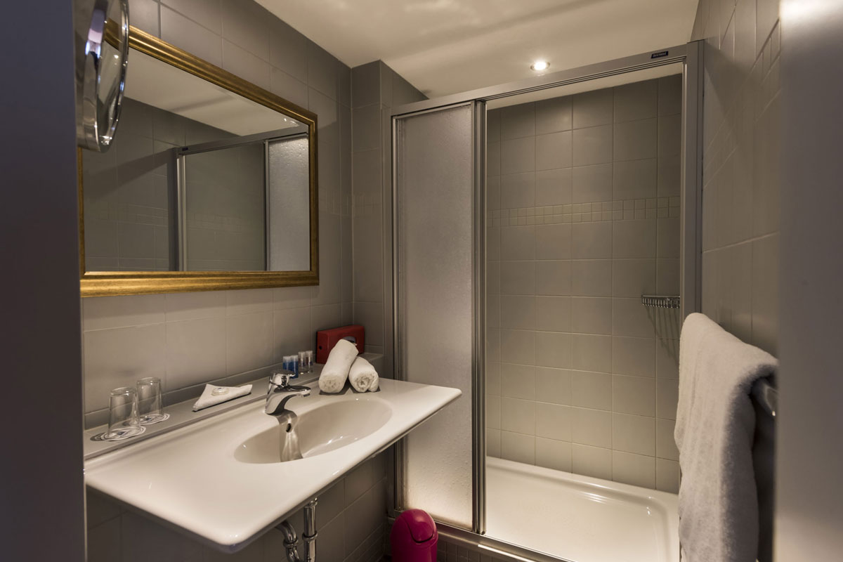 Badezimmer im Familienzimmer mit Waschbecken, großem Spiegel, Dusche und Handtüchern im Hotel Kaiserhof Heringsdorf.