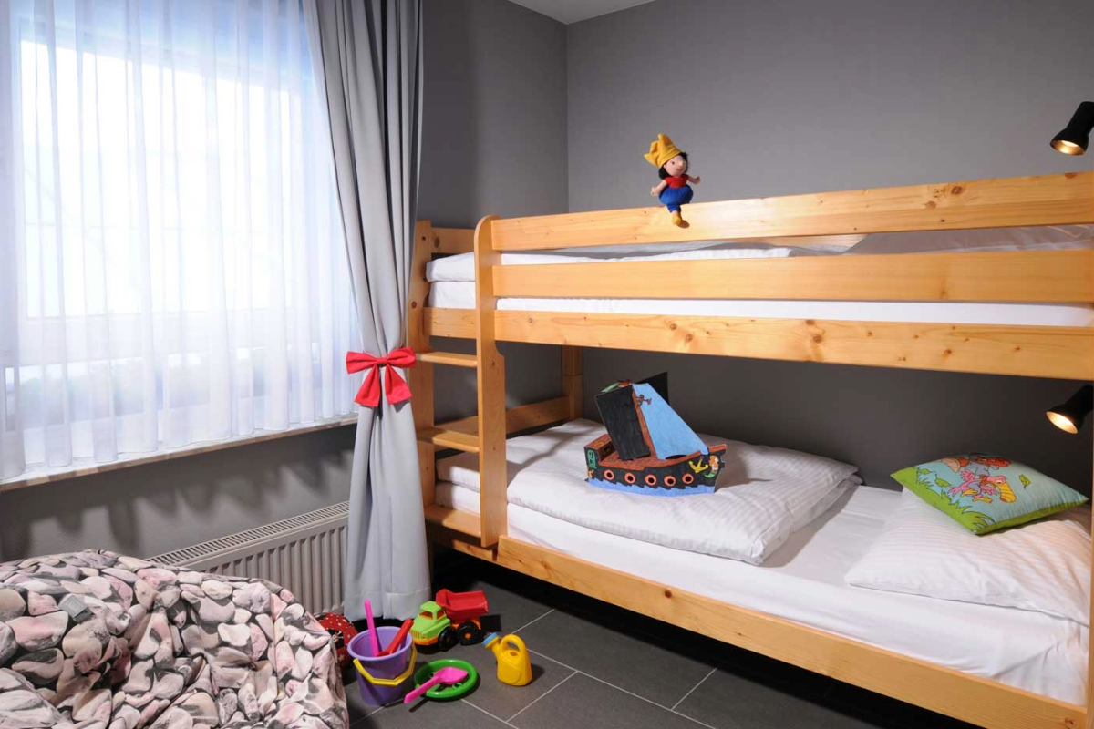 Kinderfreundliches Etagenbett mit Spielzeug und farbenfrohem Kissen im Familienzimmer im Hotel Kaiserhof Heringsdorf.