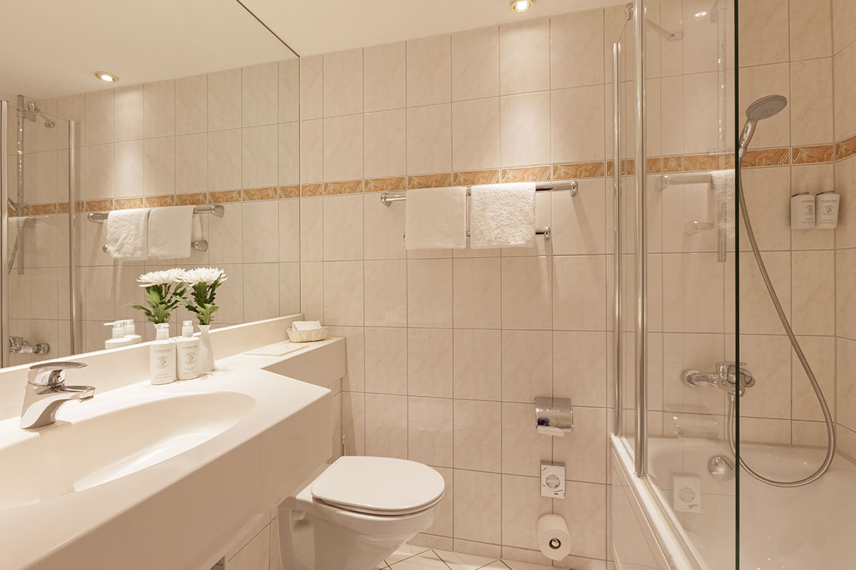 Modernes Badezimmer mit Dusche, Badewanne und eleganten Armaturen im Classic Plus Doppelzimmer mit Meerblick im Hotel Kaiserhof.