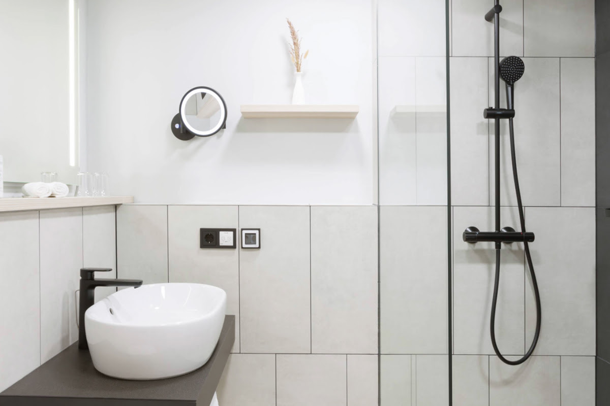 Elegantes Badezimmer in einem Deluxe-Doppelzimmer mit hellen Fliesen und hochwertiger Ausstattung im Hotel Kaiserhof Heringsdorf.