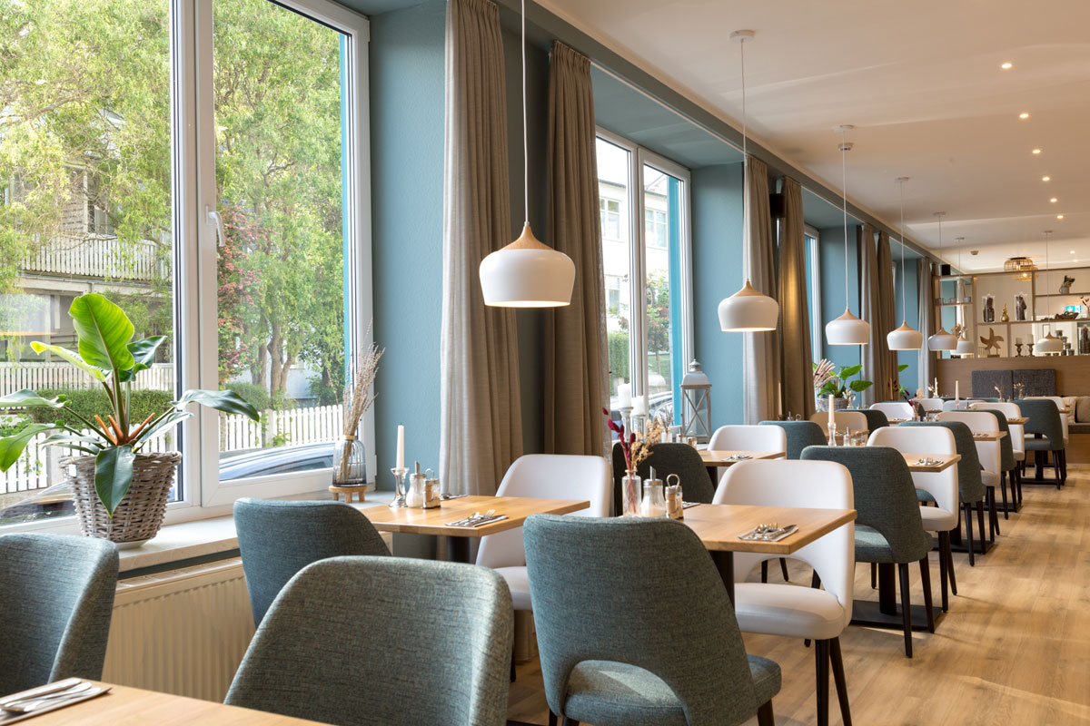 Breakfast area of the Koopmanns Hotel &amp; Lädchen, furnished with elegant tables, chairs and decorations.