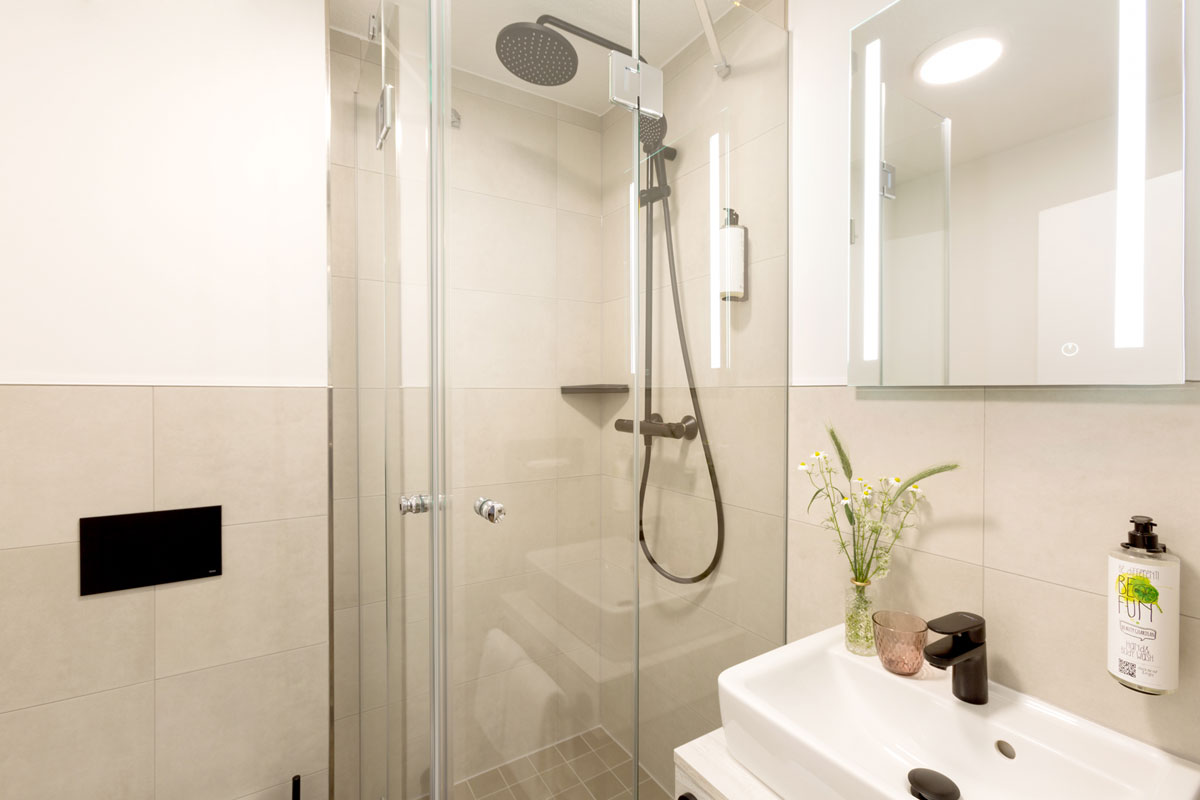 Bathroom at the Koopmanns Hotel &amp; Lädchen with a rain shower, illuminated mirror and washbasin.