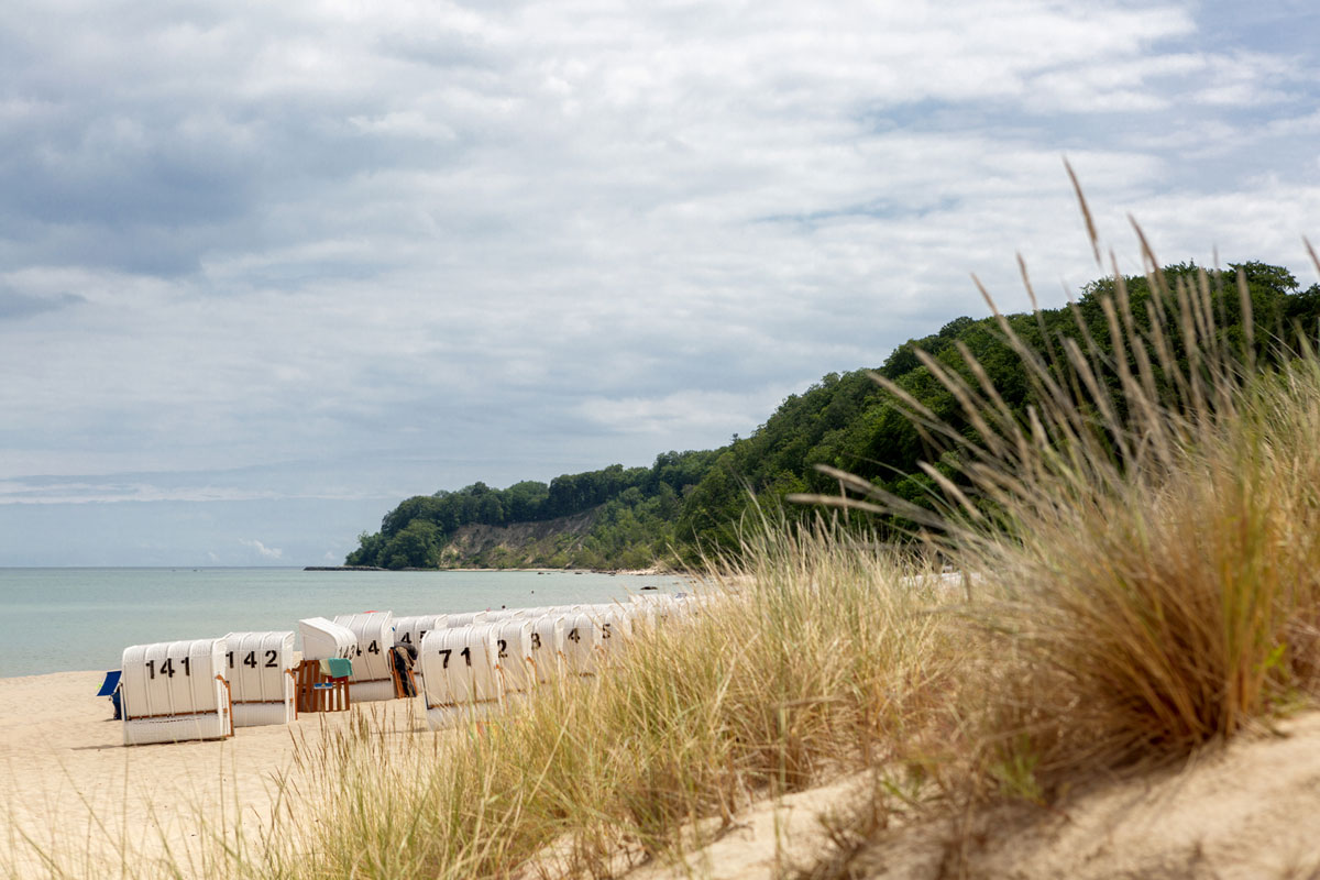 Sandy beach with beach chairs and a view of the green cliffs of Rügen on vacation at Koopmanns Hotel.